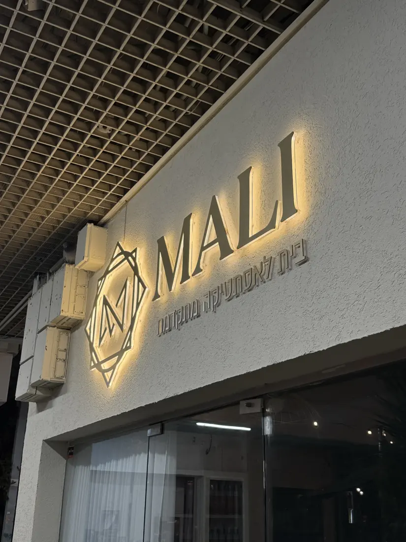 לוגו ואותיות MALI עם הילת לד אחורית על קיר לבן