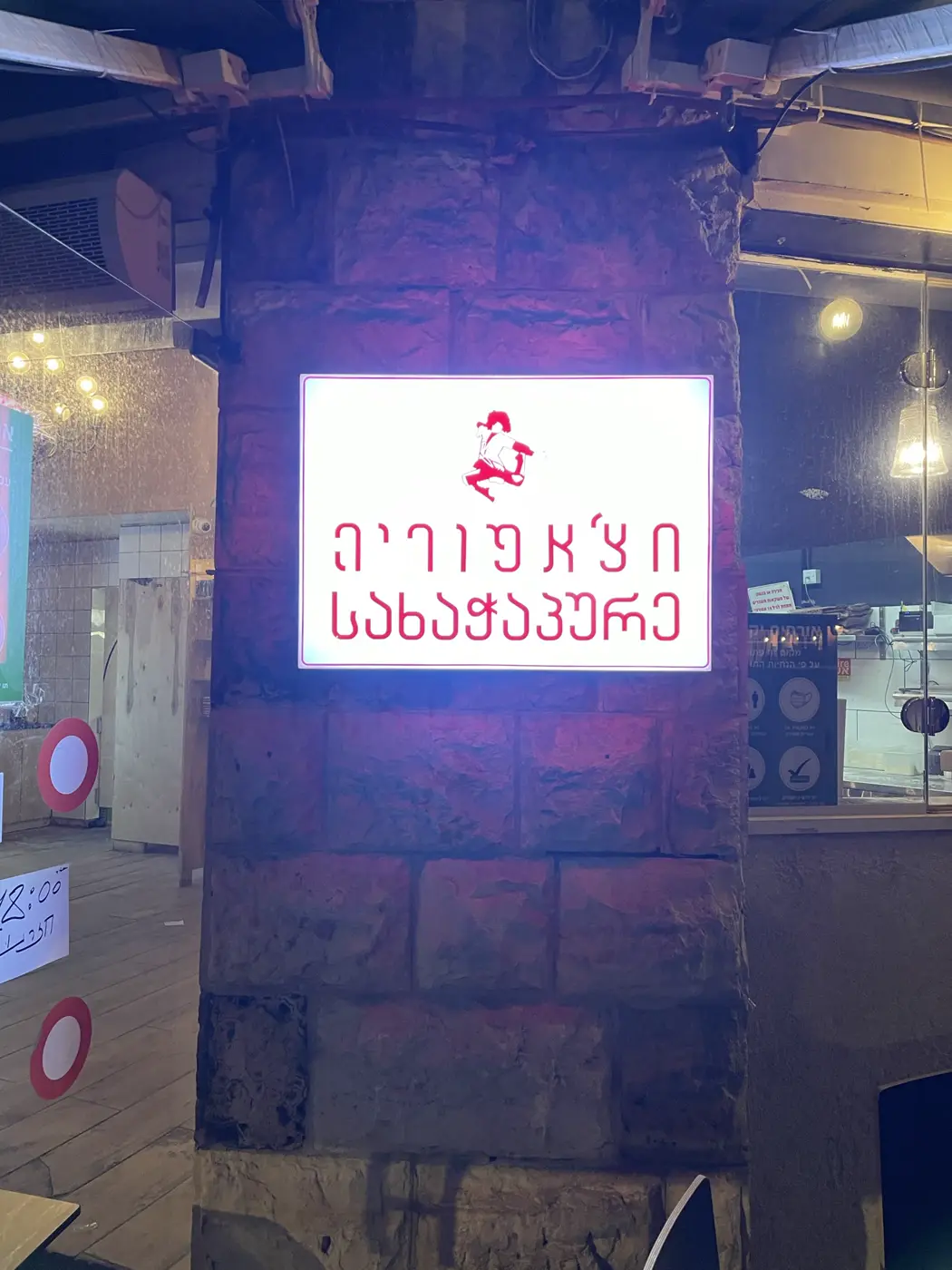 ארגז מואר לבן על עמוד אבן בכניסה למסעדה