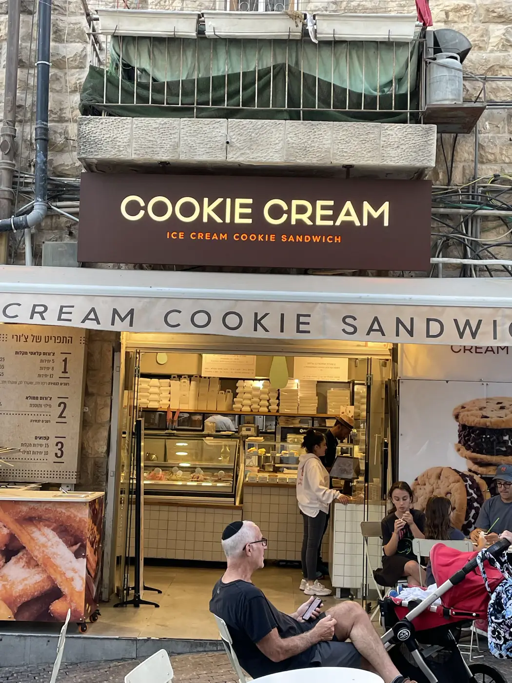 ארגז קאט אאוט חום מעל גלידריה עם אותיות לבנות וטקסט כתום מוארים, צילום חזיתי עם לקוחות