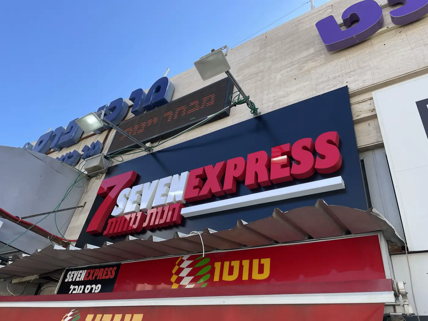 אותיות בנויות אדומות ולבנות בולטות על פאנל כחול כהה מעל חנות נוחות
