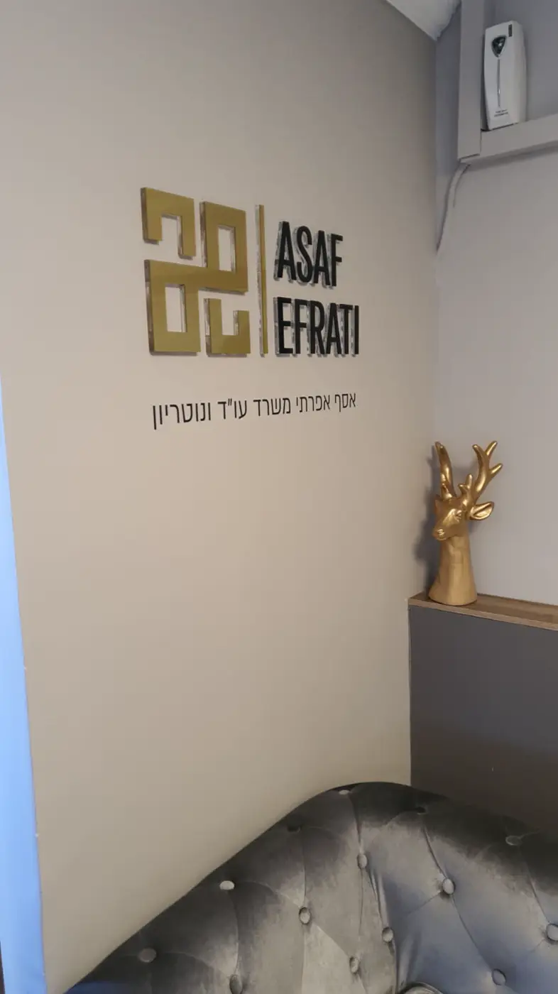 לוגו מראה זהב ואותיות שחורות עבות, וטקסט עברי בוויניל, על קיר בז׳ בחדר המתנה