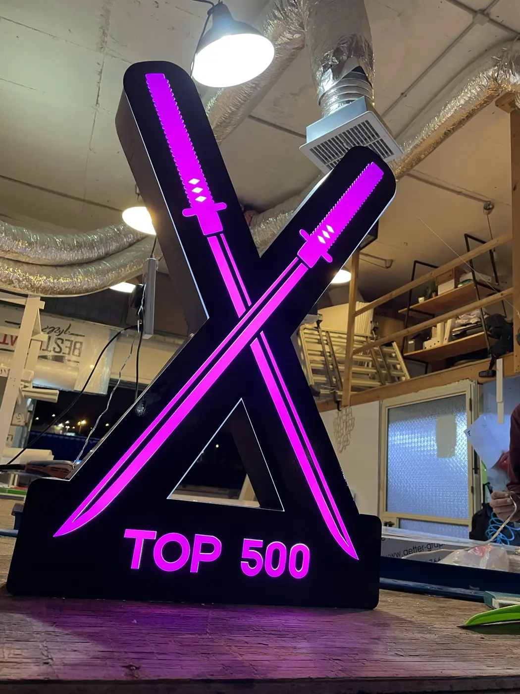 ארגז צורני שחור בצורת X עם חרבות וכיתוב מוארים בסגול, דולק במפעל